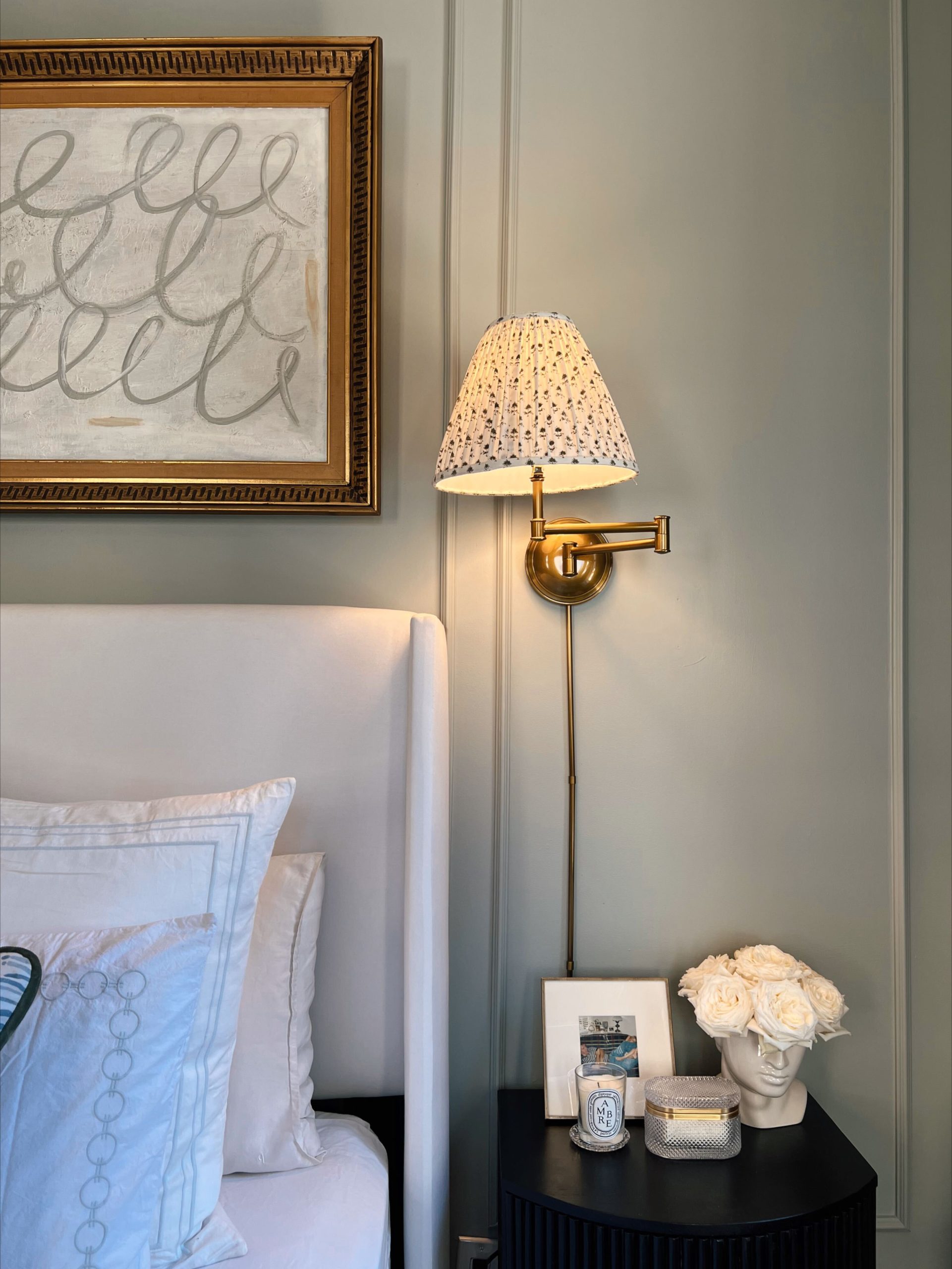 Sconce and DIY art in NYC apartment bedroom.
