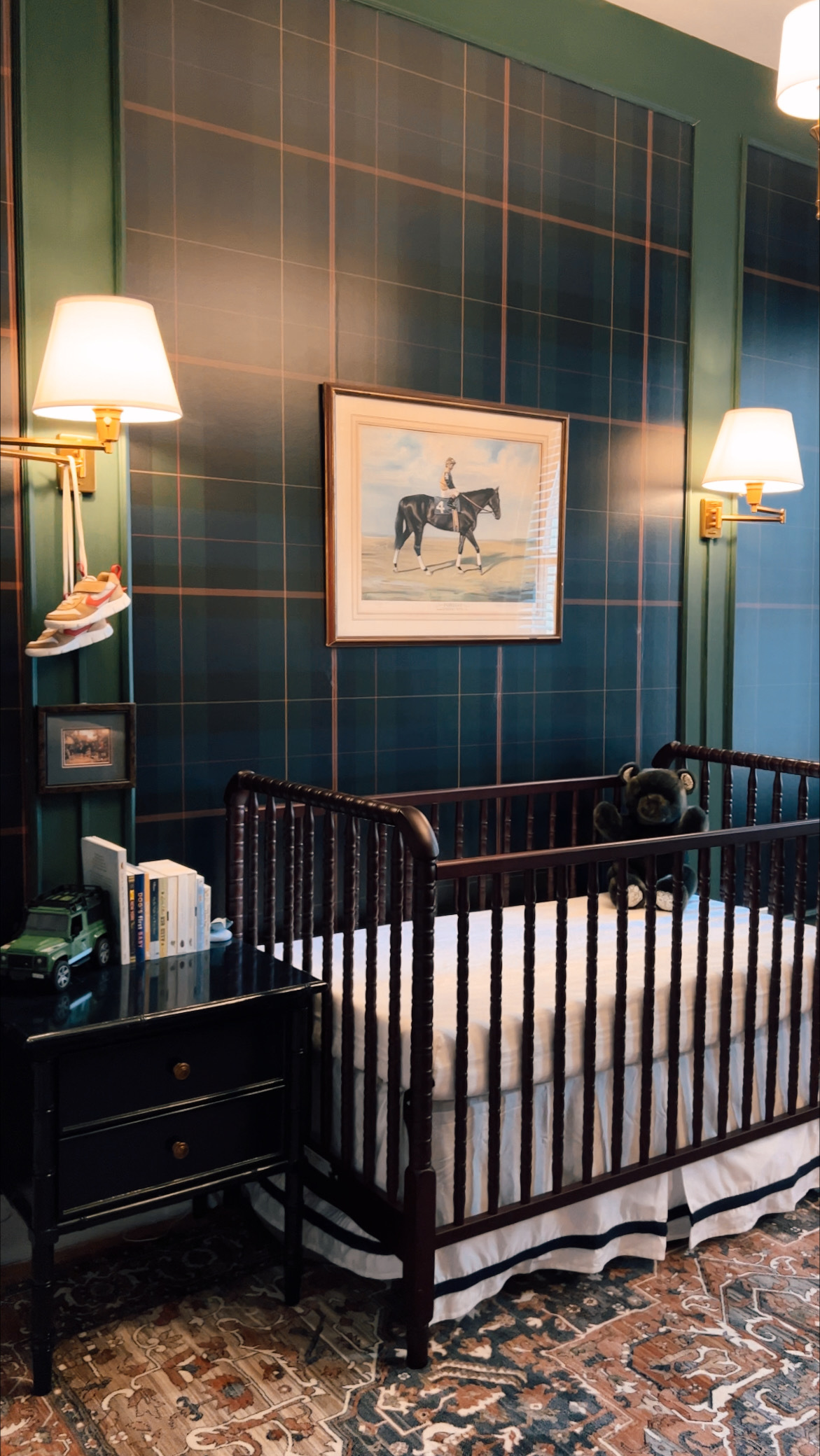 Anna's Upper East Side apartment nursery with moody colors, dark green and navy blues, with two scones for light.