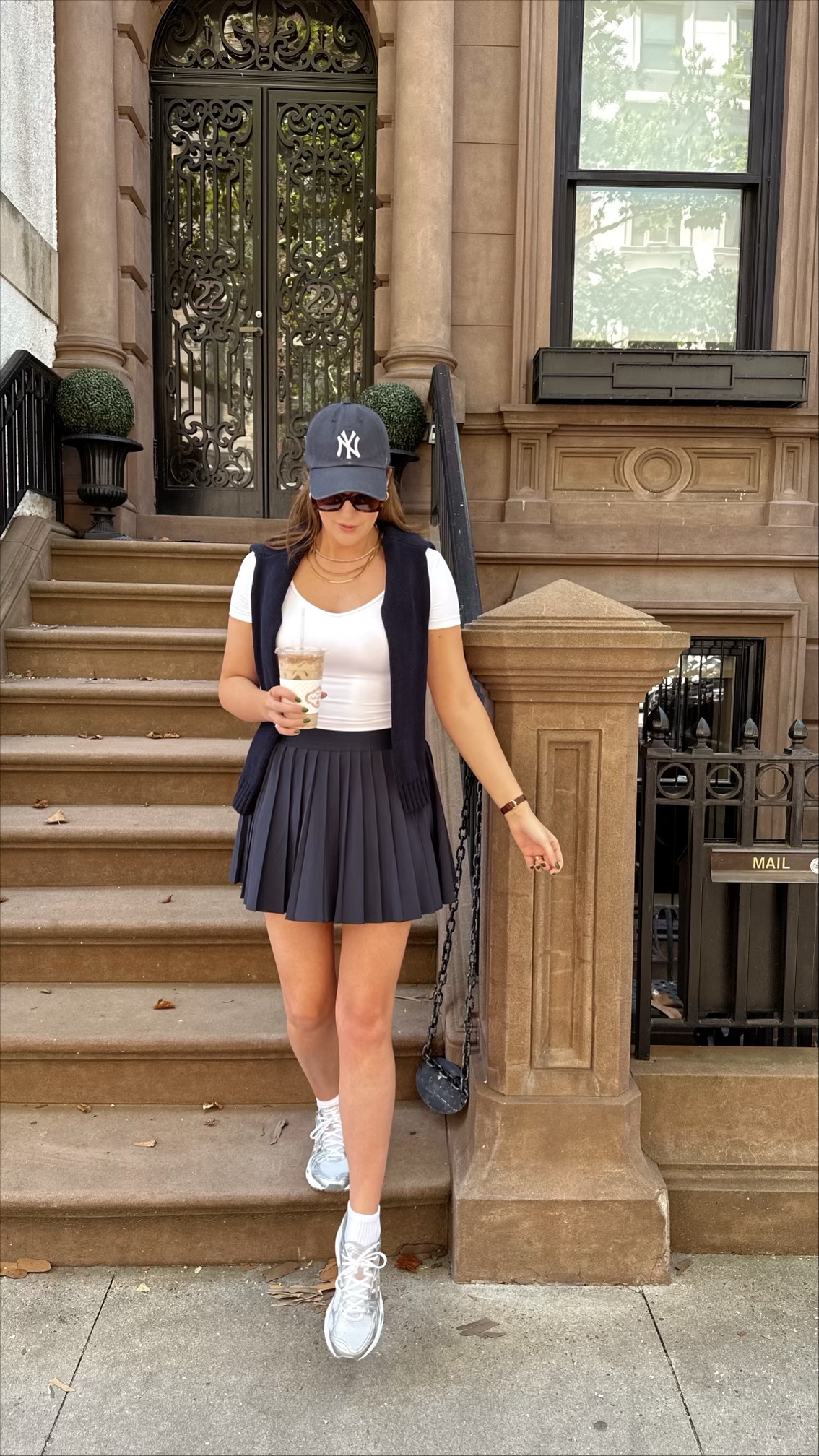 Anna wearing a sporty outfit and a hat on a New York City brownstone stoop.