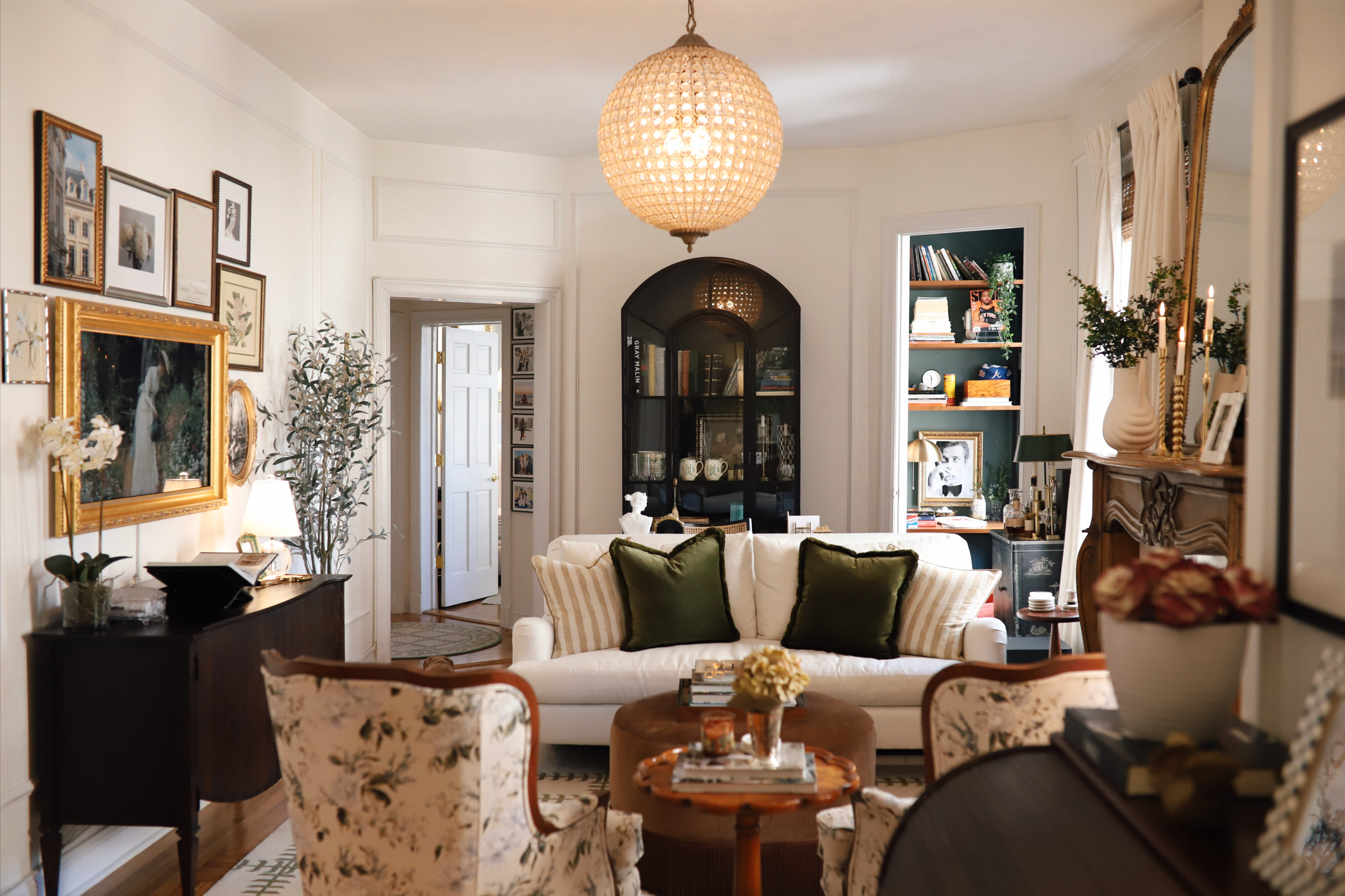 Anna's living room with a white couch, brown ottoman, and large, bright, and circular chandelier.