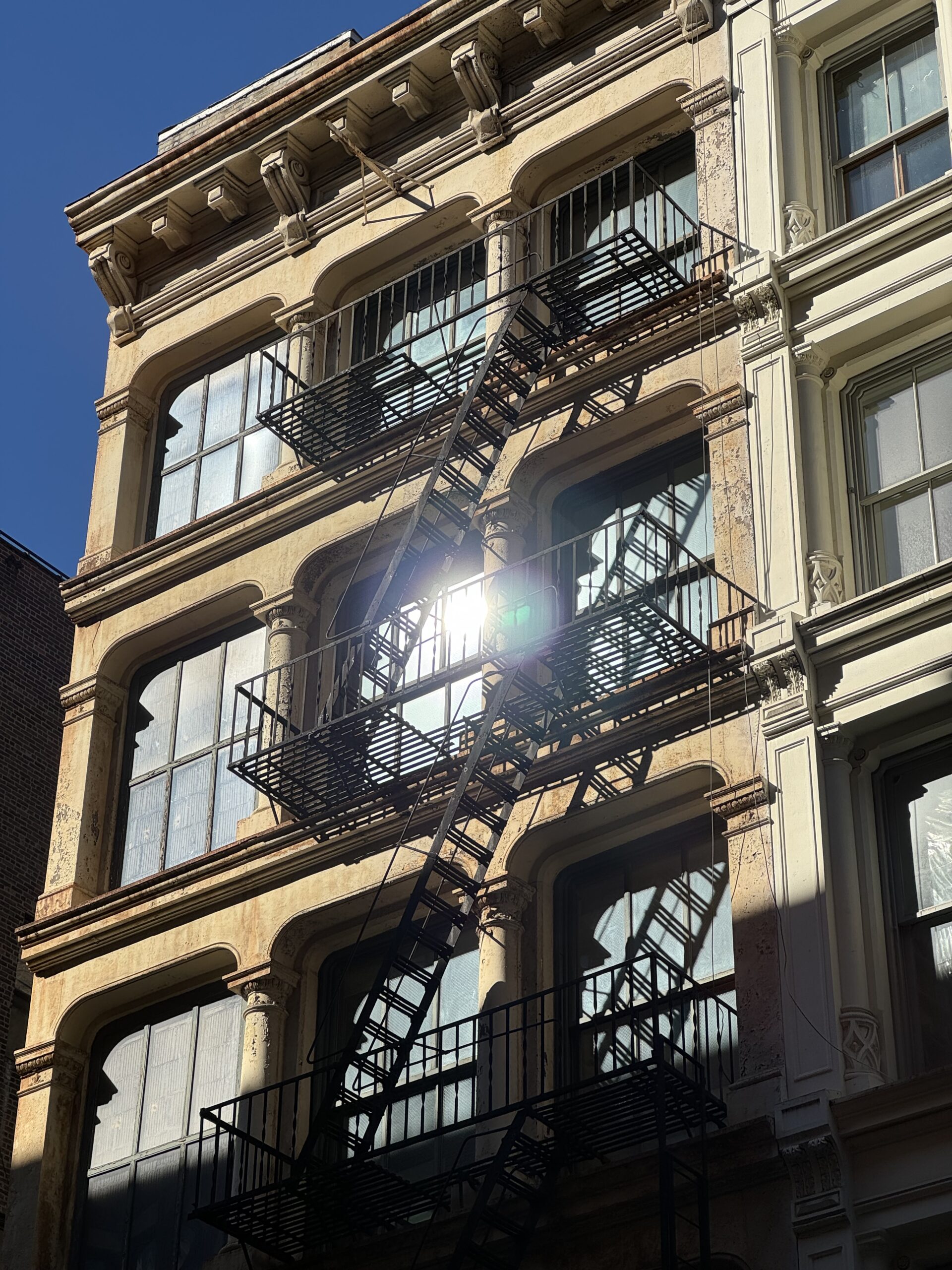 A SoHo building with large windows and a fire escape.