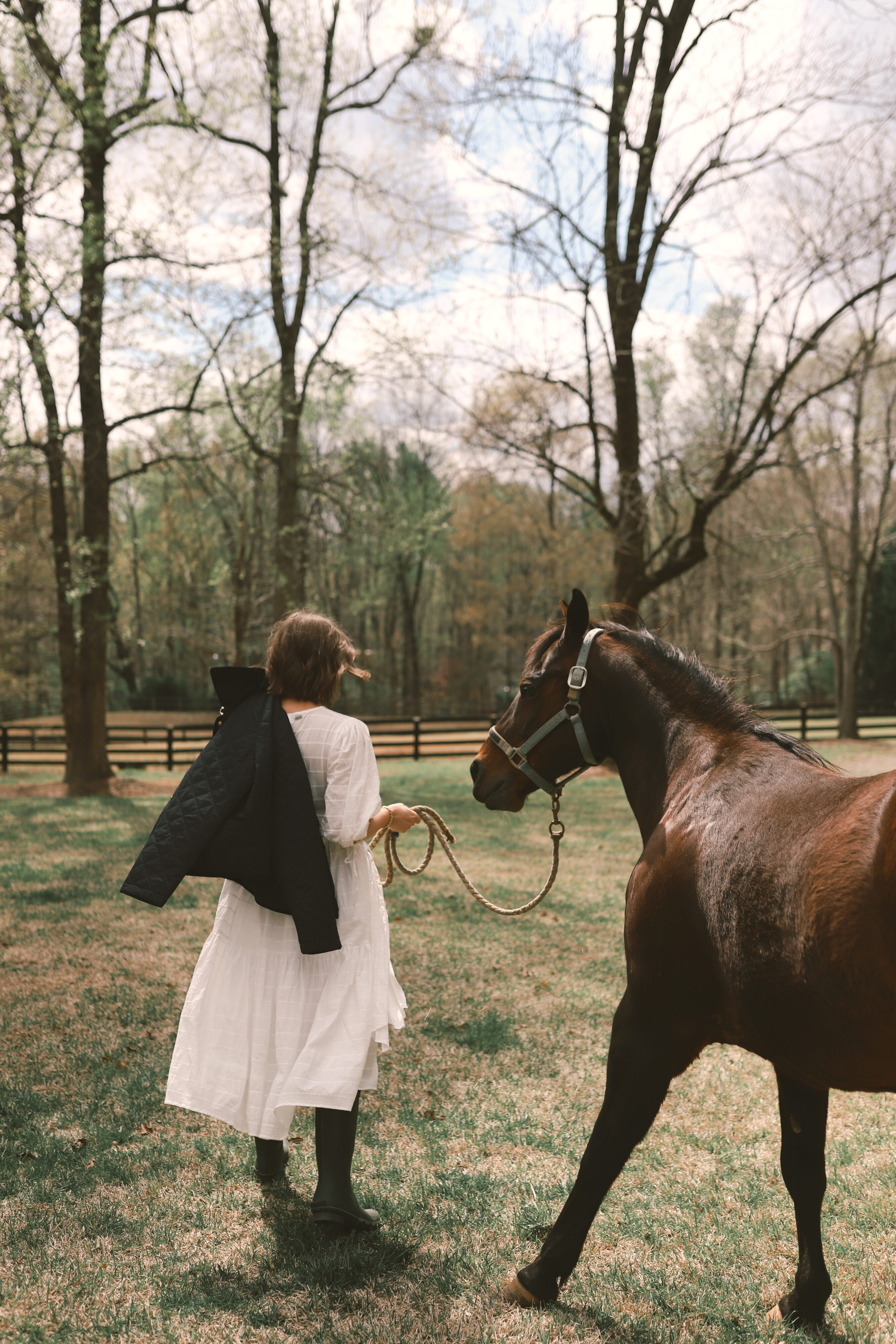 Anna in a field with a horse and a Barbour jacket over her.