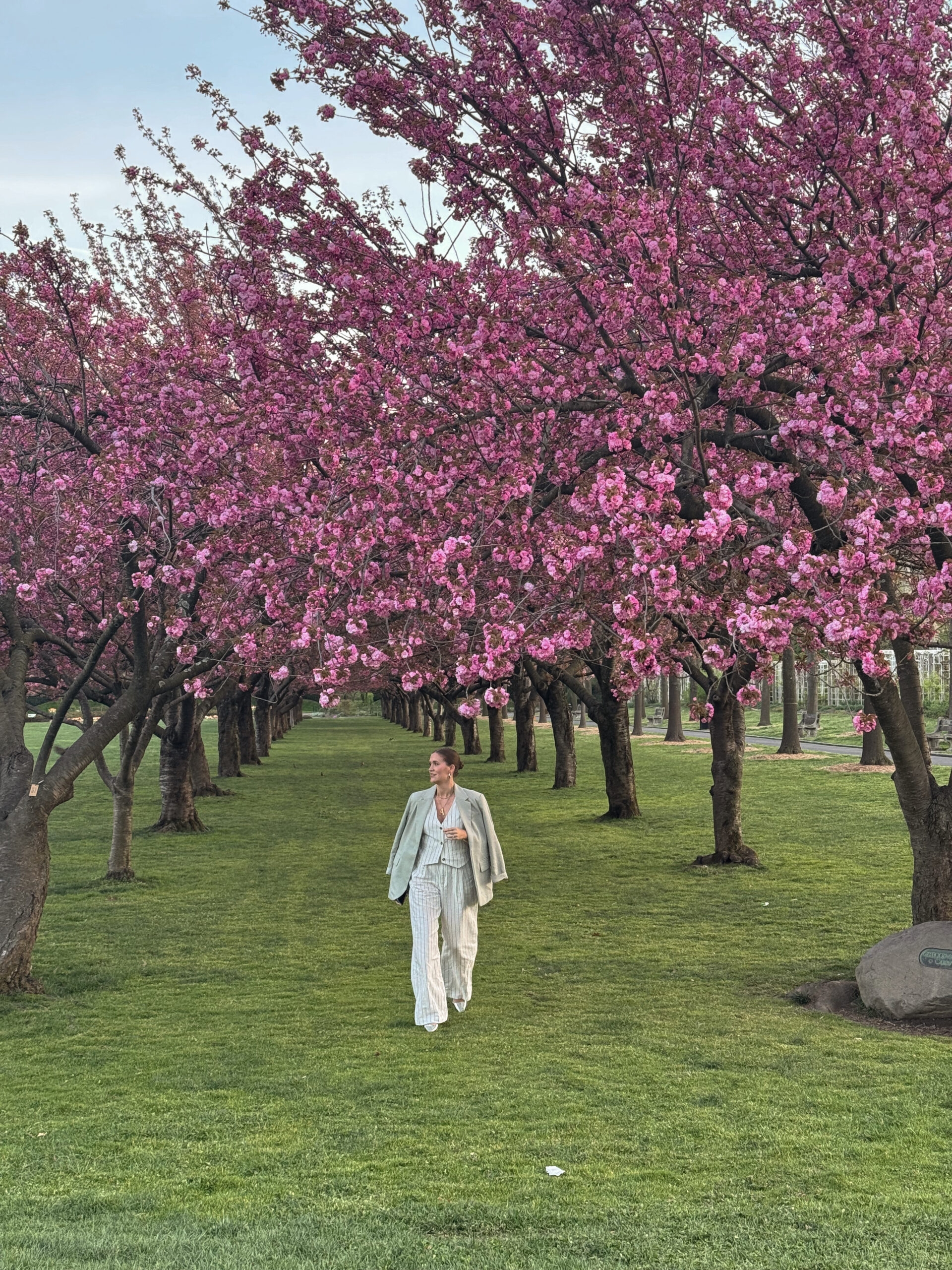 Anna walking between pink trees at the Brooklyn Botanical Garden